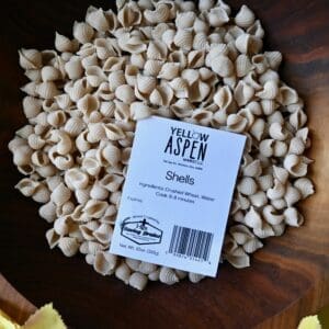Pasta shells in wooden bowl with label.