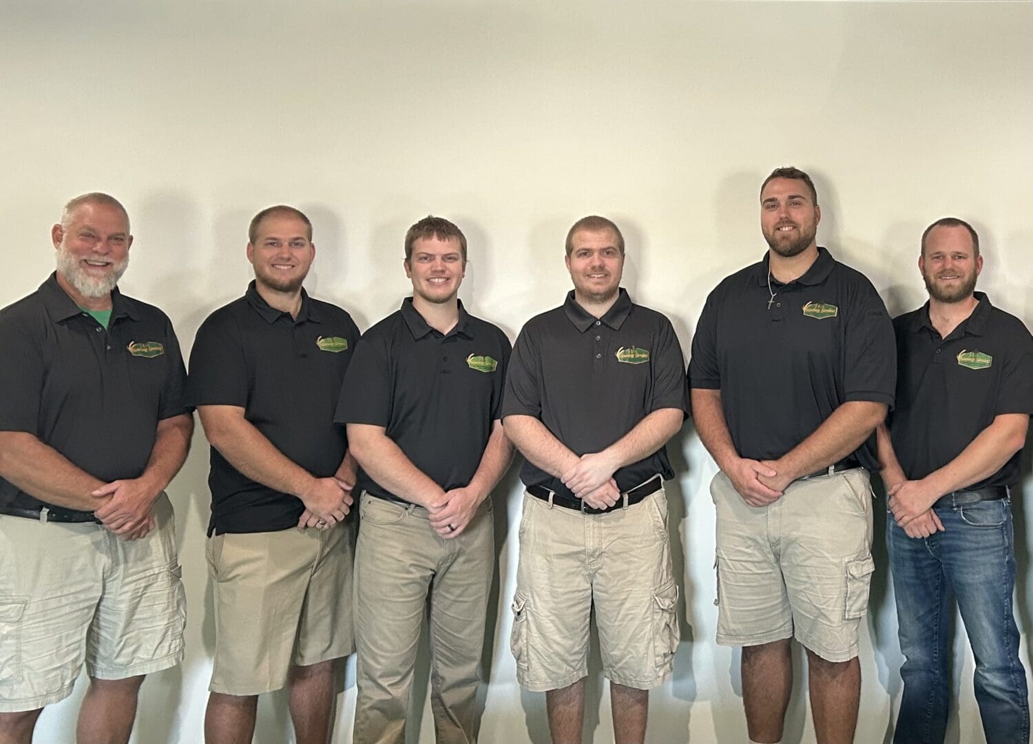 Seven men in matching black polo shirts.
